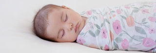 baby sleeping in a pink flower swaddle