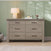 Child Craft Denman Double Dresser in Crescent Gray featuring six drawers with black metal handles, topped with a table lamp and decorative objects against a light green paneled wall.