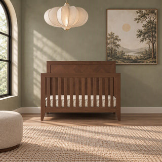 Child Craft Kieran 4-in-1 Convertible Crib in toasted chestnut, featuring a dark wood slatted design and a herringbone-patterned headboard.