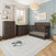 A Child Craft Redmond 4 Piece Nursery Set with Crib, Dresser with Changing Tray and Chest in dark wood, set on a light patterned rug with a whale plush toy.