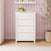 Matte white Atwood 4-Drawer Chest for a modern nursery, featuring chevron detailing on the top drawer and small hexagonal knobs.