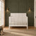 Matte white Atwood 4-in-1 Convertible Crib with a paneled headboard featuring a diagonal slat design.