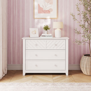 Matte White Child Craft Atwood 3-Drawer Dresser featuring a chevron pattern on the top drawer, styled with a small lamp, a potted plant, and books.