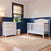 A Child Craft Hampton Arch Top 4-in-1 Convertible Crib in matte white and a matching three-drawer changing table in a nursery with navy blue wainscoting and a beige area rug.