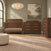 A nursery set including a wooden crib, a herringbone dresser with a changing top, and a Child Craft Kieran 5-Drawer Chest, all in a matching toasted chestnut finish with horizontal metal pulls.