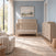 A Child Craft Kieran 4-in-1 Convertible Crib in Crescent Gray with a herringbone-patterned headboard stands in a nursery next to a matching six-drawer dresser.