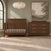 A dark wood Kieran 4-in-1 Convertible Crib in Toasted Chestnut and a matching six-drawer dresser with a changing topper in a nursery.