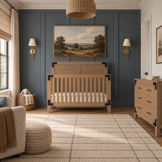 Child Craft Lucas 4-in-1 Convertible Crib in Dusty Heather with rustic finish and black corner accents, positioned in front of a dark blue paneled wall.
