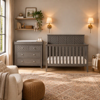 A gray Child Craft Atwood 4-in-1 Convertible Crib and matching three-drawer dresser with a changing pad on top, set in a nursery with wall-mounted lights and floating shelves.
