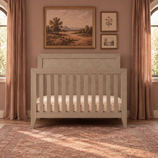 Child Craft Kieran 4-in-1 Convertible Crib in Crescent Gray, a wooden crib featuring a herringbone-patterned headboard, shown in a bedroom setting.