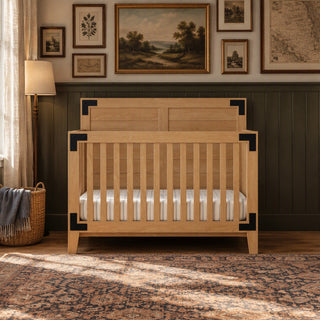 Child Craft Lucas 4-in-1 Convertible Crib in Nutmeg, featuring light wood with black metal corner brackets and a striped mattress, perfect for a modern farmhouse nursery.