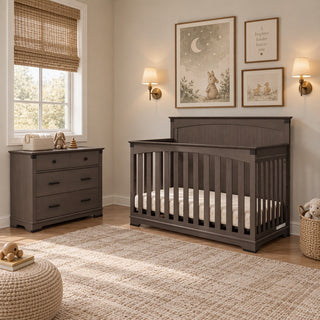 A dark gray Child Craft Redmond 3 Drawer Dresser and matching crib in a nursery.
