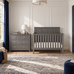 A gray Child Craft Atwood 3-Drawer Dresser, Lunar Gray with diamond-patterned drawer fronts next to a matching crib in a nursery.