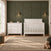 A white Child Craft Atwood 3-Drawer Dresser, Matte White sits next to a matching white slatted crib in a nursery.
