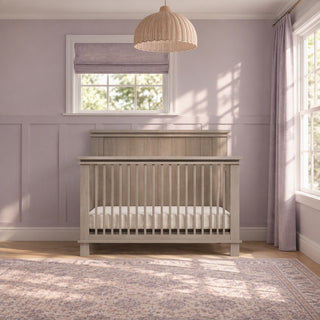 Crescent Gray Child Craft Denman 4-in-1 convertible crib crafted from pine wood with a slatted design positioned in a nursery.