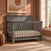 A gray, rectangular Child Craft Denman 4-in-1 Convertible Crib in Midnight Gray with a rectangular headboard.