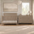 A light gray Kieran 6-Drawer Double Dresser with six horizontal silver pulls stands next to a matching crib in a nursery.