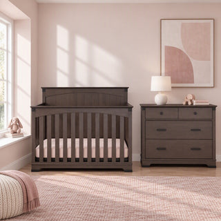 A dark gray Child Craft Redmond crib and matching Redmond 3 Drawer Dresser in Dapper Gray in a nursery.