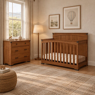 A wooden baby crib and matching Coach Cherry Redmond 3 Drawer Dresser by Child Craft in a nursery.