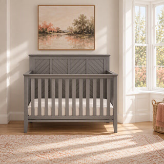 Child Craft Atwood 4-in-1 Convertible Crib in Lunar Gray, featuring a chevron-patterned headboard and slatted sides in a nursery with baby-safe finishes.