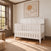Matte white Atwood 4-in-1 Convertible Crib with a paneled headboard featuring diagonal trim and baby-safe finishes.