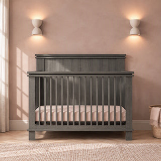 Child Craft Denman 4-in-1 Convertible Crib in Midnight Gray, made of pine wood with a dark gray finish, slatted sides, and a solid headboard.