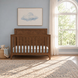 Child Craft Kieran 4-in-1 Convertible Crib in toasted chestnut, featuring a herringbone-patterned headboard, placed in a nursery with a window and a framed cloud print.