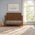 Child Craft Kieran 4-in-1 Convertible Crib in toasted chestnut, featuring a herringbone-patterned headboard, placed in a nursery with a window and a framed cloud print.