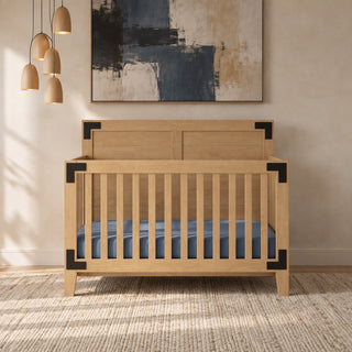A rustic Lucas 4-in-1 Convertible Crib in Nutmeg, this light brown wooden piece features dark metal corner brackets and a blue mattress.