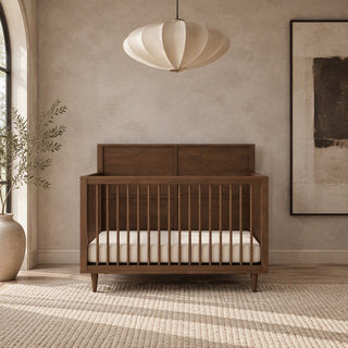 Child Craft Surrey Hill 4-in-1 Convertible Crib in toasted chestnut with a paneled headboard and a white mattress.