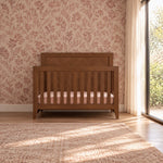 A toasted chestnut Child Craft Kieran 4-in-1 Convertible Crib featuring a slatted design and a mattress.
