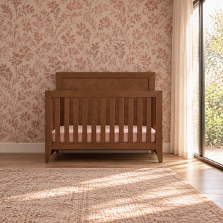 A toasted chestnut Child Craft Kieran 4-in-1 Convertible Crib featuring a slatted design and a mattress.