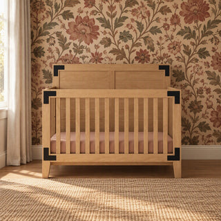 Child Craft Lucas 4-in-1 Convertible Crib in nutmeg light wood with black metal corner brackets and a pink mattress.