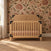 Child Craft Lucas 4-in-1 Convertible Crib in nutmeg light wood with black metal corner brackets and a pink mattress.