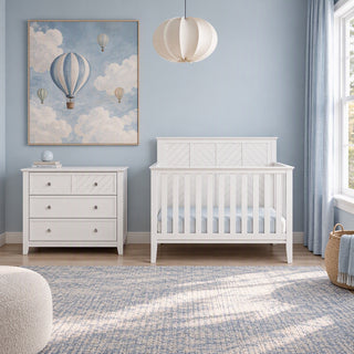 A white Child Craft Atwood 3-Drawer Dresser, Matte White, sits next to a matching white crib in a nursery.