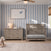 Gray wooden Denman Double Dresser, Crescent Gray with six drawers next to a matching crib in a room with blue striped wallpaper.