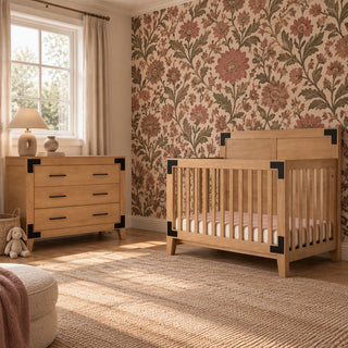 Child Craft Lucas Dresser, Nutmeg and matching crib with black corner hardware in a nursery with floral wallpaper.