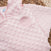 Close-up of a pink HALO Swaddle Plushy Dot Velboa TOG 3.0, featuring a textured polka dot design and an embroidered Back is Best logo with a sleeping baby. The soft fabric promotes healthy hip development and feels cozy.