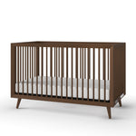 The Child Craft Cranbrook 4-in-1 Convertible Crib in Toasted Chestnut features vertical slats, angled legs, and a white mattress—an ideal modern mid-century nursery furniture piece set against a plain white background.