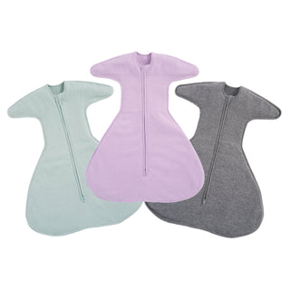 The HALO SwaddleStretch Newborn Swaddle Bundle includes three cotton swaddles in pastel green, light purple, and dark gray with central zippers and wing-like sleeves, displayed side by side on a white background.