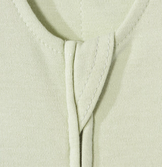 Close-up of the neckline on the HALO Swaddle 100% Cotton TOG 1.5 in light beige or pastel yellow, showcasing detailed stitching and a center folded overlap for a cozy, adjustable fit.