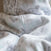 A close-up view of the Wearable Blanket Micro-Fleece TOG 1.0 by HALO showcases its soft, pale gray microfleece with a subtle abstract animal pattern, offering a cozy and warm texture ideal for safe sleep or lounging comfort.