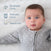 A baby rests on HALOs Essential Breathable Crib Mattress, wearing a light grey outfit. Features for comfortable sleep include a breathable cover, washable and waterproof design, highlighted by icons.
