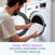 A man places the white, breathable cover of an Essential Breathable Crib Mattress into a front-load washing machine, with text reading: Unzip. Wash. Repeat. Machine-washable cover for easier cleanup.