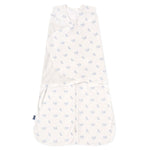 The HALO Swaddle 100% Cotton TOG 1.5 in white features light blue floral patterns on soft fabric, with adjustable wings for a snug fit and promotes healthy hip development. The widened bottom ensures comfort, and theres a small tag on the left edge.