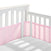 A white crib with slatted sides displays attached light pink HALO Breathable Mesh Crib Liners for a full-sized crib. Built to meet infant bedding safety standards, the empty crib shows gentle sunlight shadows on the white mattress.