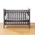 A dark gray wooden baby crib with vertical slats stands on a light wood floor, featuring a HALO white mattress and the HALO Breathable Mesh Crib Liner for Full Sized Solid End Crib, elegantly secured with ties. The plain white background ensures the focus remains on this charming nursery essential.