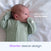 A baby in a light green HALO SwaddleStretch™ Newborn Swaddle TOG 0.5 with short sleeves lies on a white blanket. Text on the image reads, Helps prevent startle reflex and Shorter sleeve design. Featuring HALO’s hip-healthy sleep sack design, this stretchy swaddle provides comfort and security for your little one.