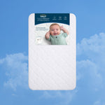 Rectangular white HALO Bedside Sleeper DreamWeave Breathable Pad with a scalloped pattern, featuring a product label showing a smiling baby and icons for the pad’s hypoallergenic and washable features.