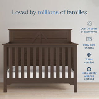 A brushed truffle Woodland 4-in-1 Convertible Crib by Child Craft with white bars rests on a light floor. "Loved by millions of families" is above, with icons for 70+ years experience and safety. Discover Child Craft’s trusted crib today.